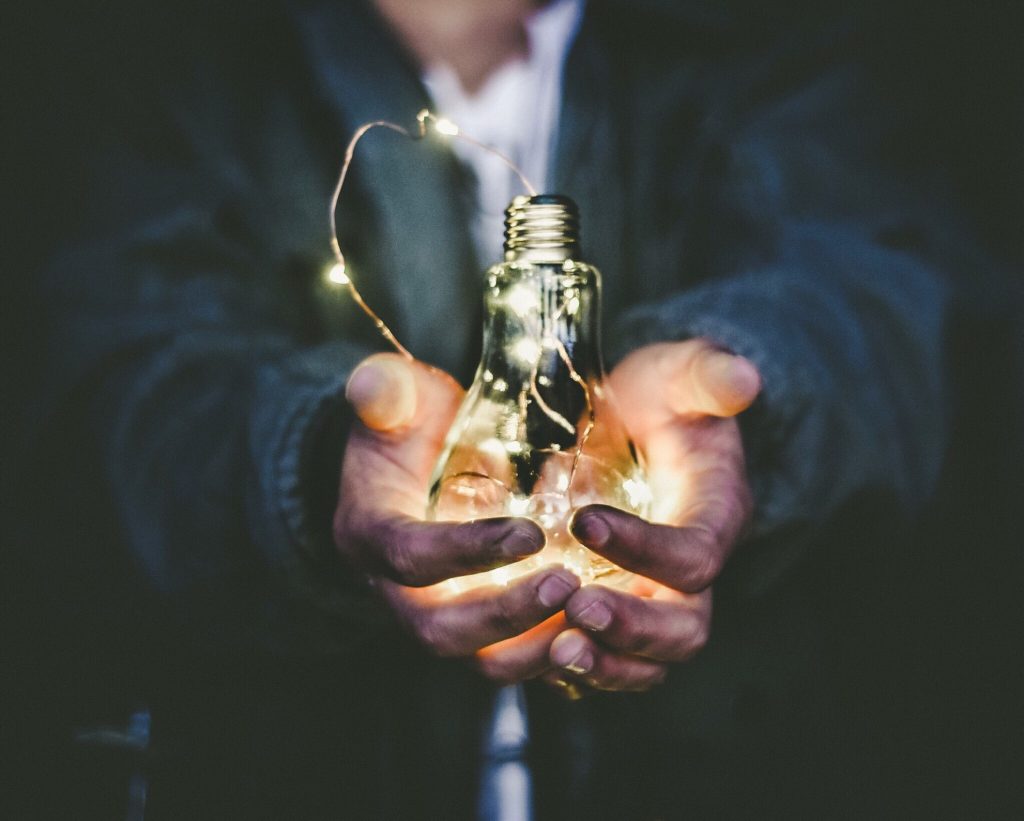 person holds a lightbulb with fairy lights