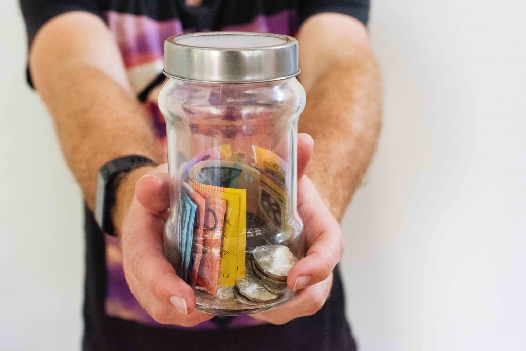 Hand holding jar with Australian currency